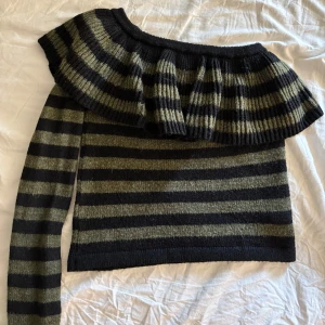 Randig offshoulder tröja från Pull&Bear - Säljer en snygg randig tröja från Pull&Bear i svart och grön. Tröjan har en unik offshoulder-design med volang. Hör av dig vid frågor! 