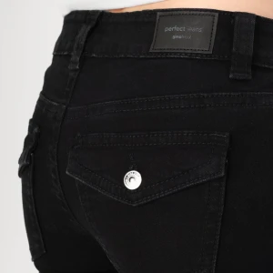 Svarta jeans från Gina Tricot - Snygga svarta jeans från Gina Tricot med en tight passform. De har en låg midja och är dekorerade med silverfärgade knappar. Perfekta för en stilren look.