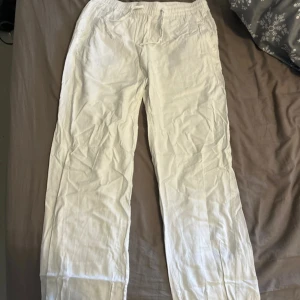 Vita linnebyxor - Säljer ett par vita linnebyxor med elastisk midja. Perfekta för varma dagar med sin lätta och luftiga känsla. Byxorna har en avslappnad passform och är enkla att matcha med olika toppar.