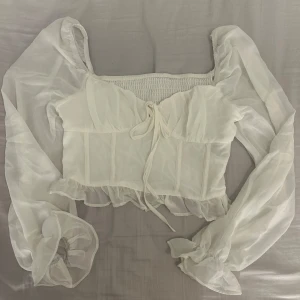 Vit blus med långa ärmar - Säljes en super söt vit blus med volang detaljer, köpt från shein för nått år sedan men har aldrig blivit använd. 