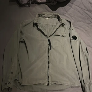 Grön jacka med dragkedja - Säljer nu min cp company overshirt jag fått ärva utav brorsan storleken är L och tyvärr lite stor på mig. Den är riktigt fet och är nyskick har knappt används om ni är sugna är det bara o höra av er