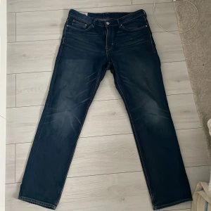 Blå jeans från &Denim - Säljer ett par klassiska blå jeans från &Denim i regular fit. De har en traditionell femficksdesign och är tillverkade i slitstarkt denim. Perfekta för en avslappnad stil.