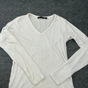 Vit ribbad långärmad tröja från 157 - Säljer en stilren vit ribbad tröja från 157 i storlek XS. Tröjan har en v-ringad hals och långa ärmar, perfekt för lager på lager-stil. Passar till både jeans och kjol. 🖤