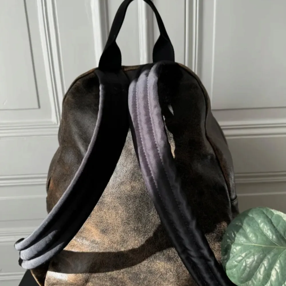 Snygg brun ryggsäck i skinn med ett stilrent märke på framsidan. Ryggsäcken har en praktisk dragkedja och en klassisk design som passar perfekt för vardagsbruk. Den har en rymlig huvudficka och en mindre ficka framtill för enkel åtkomst till dina saker.. Laukut & Käsilaukut.