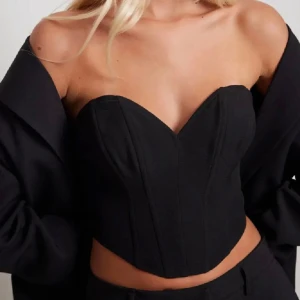 Svart korsett - Snygg svart korsett med en elegant och stilren design. Den är axelbandslös och har en figurnära passform som framhäver midjan. Perfekt för en kväll ute eller en speciell tillställning. Helt ny med prislapp kvar💗