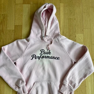 Rosa hoodie från Peak Performance - Säljer en gosig baby rosa hoodie från Peak Performance. Den har en klassisk känguruficka och justerbar huva med dragsko. Sparsamt använd.