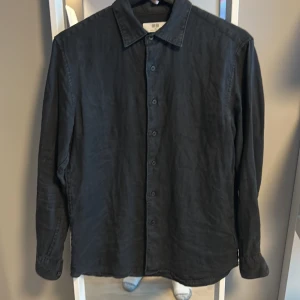 Svart långärmad skjorta från Uniqlo - Svart linneskjorta från uniqlo den är xs och kostar runt 500kr ny pris men säljer den för 150kr. 