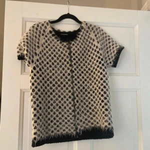 Svart och vit kortärmad tröja från Intimissimi - Säljer en unik svart och vit kortärmad tröja från Intimissimi. Tröjan har ett intressant mönster med fluffiga detaljer och en rund halsringning. Perfekt för att ge din outfit en speciell touch. Pris är ikke hugget i sten!