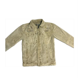 Overshirt grön - Snygg grön overshirt med broderade detaljer på bröstet. Jackan har en klassisk krage och knäppning framtill. Perfekt för en avslappnad stil.