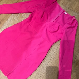 Rosa klänning från Nelly - Säljer en snygg rosa klänning från Nelly med långa ärmar och en dragkedja i ryggen. Klänningen har en figurnära passform och är perfekt för en kväll ute. Oanvänd!