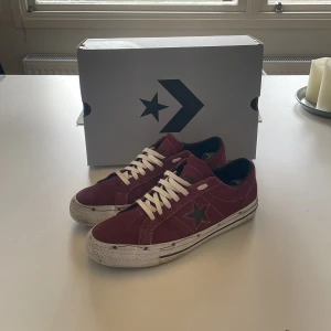 Röda sneakers från Converse - Snygga röda Converse sneakers i mocka med vita snören och en stjärndetalj på sidan. Skorna har en klassisk design med rund tå och vit sula. Perfekta för en avslappnad stil. Box och original snöre tillkommer!