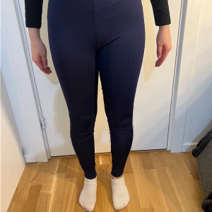 Mörkblå leggings från Fila med logga längs benet - Säljer ett par mörkblå leggings från Fila med vit logga längs hela sidan av benen. De har en tight passform och hög midja, perfekta för träning eller en sportig look.