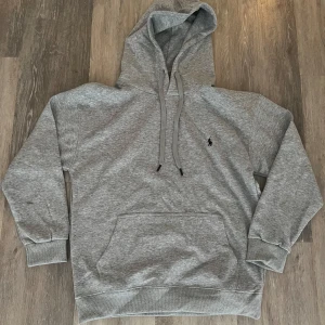 Grå hoodie från Ralph Lauren - Hej, säljer min polo ralph lauren hoodie som jag använt ett tag men som fortfarande är i fint skick.  Storlek L.   Säljer då jag har växt ur den. Kontakta om ni vill ha fler bilder eller funderingar.