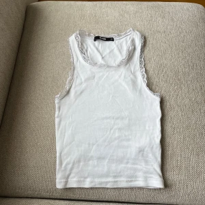 Vit spetskantad linnetopp från BikBok - Säljer en vit linnetopp från BikBok i storlek XS. Toppen har fina spetsdetaljer längs halsringning och ärmhål. Tillverkad i bomull, perfekt för sommaren. Köptes secondhand men aldrig använd. Den är inte så stretchig och därför passar den xs/xxs. 