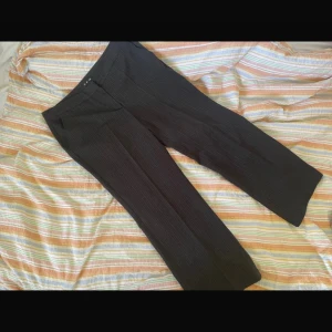 Mörkbruna kostymbyxor med diskreta ränder från CPH - Säljer ett par mörkbruna kostymbyxor från CPH med tunna, diskreta ränder. Byxorna har rak passform och klassisk midja. Perfekta för en stilren look och passar till många olika outfits.