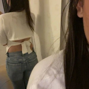 Vit croppad topp med knyt i ryggen - Säljer en vit croppad topp med korta ärmar och snygg knytning i ryggen. Toppen har en tight passform och är perfekt till jeans eller kjol. Enkel och stilren design som passar till många tillfällen.