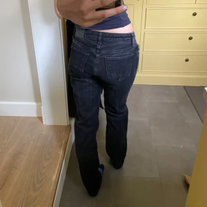Svarta raka jeans - Säljer ett par svarta jeans med rak passform och klassisk femficksdesign. Jeansen har låg midja och stängs med dragkedja och knapp. Perfekta till vardags för en stilren look.
