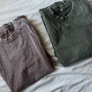 Två basic t-shirts i tvättad look - Köp 1 för 80kr, 2 för 140kr. Säljer två stilrena t-shirts i tvättad look, en i dämpad grön och en i dov brunlila färg. Båda har rund halsringning och korta ärmar. Perfekta för en avslappnad och trendig stil.😮‍💨Säljer då min bror aldrig använt dem, precis som ny🤩‼️