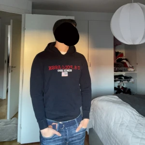 Mörkblå hoodie från Ralph lauren U.S. Polo Assn. - Säljer en mörkblå hoodie från Ralph lauren U.S. Polo Assn. med röd och vit broderad logga och amerikansk flagga på bröstet. Klassisk huva och ribbade muddar. Perfekt för en avslappnad stil. Står M men passar mer som S