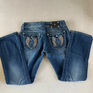 Mörkblå miss me bootcut jeans - Miss Me Jeans - Som Nya! Midjemått från höftsöm till höftsöm: Cirka 38cm. Säljer ett par supercoola mörkblå Miss Me bootcut jeans med de ikoniska vingarna på bakfickorna. Jeansen är använda endast ett fåtal gånger och är i toppskick. Storlek: W28 Detaljer: *   Mörkblå denim av hög kvalitet *   Unik design med vingar på bakfickorna *   Bekväm passform som framhäver dina former *   Inga defekter eller slitage- i nyskick! Kontakta mig vid intresse eller frågor!😊