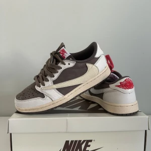Nike Air Jordan 1 Low Travis Scott x Fragment kan byta mot Louboutins size 39 eller Valentino size 39 - Nike Air Jordan 1 Low Travis Scott x Fragment med brun och vit ovandel, beige swoosh och röda detaljer. Ena skon har röda skosnören, den andra bruna. Ikonisk omvänd swoosh och broderad logga på hälen. Pris kan förhandlas, kommer ej med kvitto. Kan byta mot Louboutins eller valentinos size 39-40 typ