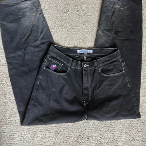 Svarta polar bigboy jeans - Svarta jeansbyxor från Acid Bros med vit kontrastsöm och broderad detalj på myntfickan. Klassisk femficksmodell med raka ben och normal passform. Perfekta för dig som gillar streetwear och vill ha något unikt i garderoben.