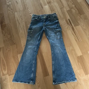 Blå flared leg adjustable waist jeans från H&M - Säljer ett par blåa jeans från H&M. Flera fickor på sidorna. Säljer för att de inte är min smak längre dem är som nya använd ett få tal gånger.