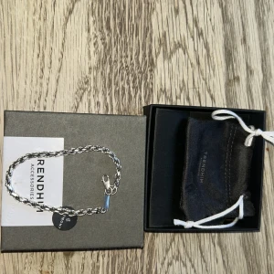 Silverfärgat armband från Trendhim - Snyggt flätat armband i silverfärg från Trendhim. Armbandet har en robust kedjedesign och ett diskret lås med märkets logga ingraverad. Perfekt accessoar för att lyfta din stil.