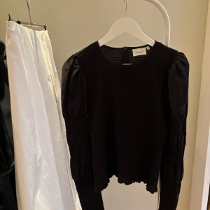Gestuz blus  - Snygg svart blus från Gestuz med långärmade puffärmar och en smockad textur. I storlek 40, tycker den passar snyggt på mig som är en strl 36 men det är en smaksak. 