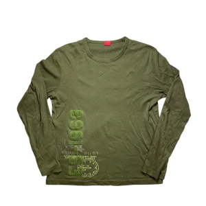 Olivgrön långärmad tröja från Esprit - Säljer en mörkgrön långärmad tröja från Esprit med tryck i grönt och vitt framtill. Tröjan har rund halsringning och är tillverkad i mjuk bomull. Perfekt för en avslappnad stil.