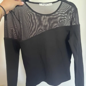 Svart meshtröja  - Säljer en svart långärmad topp från NA-KD med transparent mesh upptill och över axlarna Perfekt middags och festtopp. Endast använd 1 gång 
