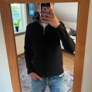 Svart stickad tröja med quarter zip - Säljer en svart stickad tröja med quarter zip. Tröjan har lång ärm och en klassisk, enkel design som passar till mycket. Perfekt för kyligare dagar och enkel att matcha med jeans eller andra byxor.