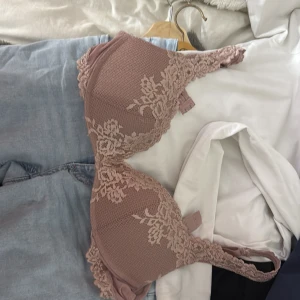 Rosa spets-bh från Intimissimi - Säljer en superfin rosa bh från Intimissimi med vacker spetsdetalj och blommönster. Bh:n har vadderade kupor och justerbara axelband. Perfekt för dig som vill ha något både snyggt och bekvämt.