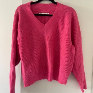 Rosa stickad v-ringad tröja  - Säljer en stickad rosa tröja från Only med v-ringning och långa ärmar. Perfekt för att liva upp garderoben med en färgklick. Tröjan är mjuk och skön, passar till många olika outfits. Perfekt en sommarkväll 