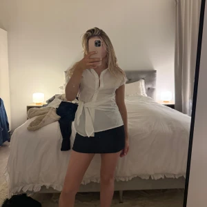 Vit omlottblus med knytband - Säljer en stilren vit blus med kort ärm och snyggt knytband i midjan.