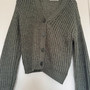 Grön stickad kofta från H&M - Mysig grå stickad kofta från H&M med v-ringning och stora knappar framtill. 