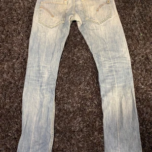 Ljusblå jeans från Dondup  - Säljer ett par ljusblå jeans från Dondup med klassisk femficksdesign och raka ben. Jeansen har snygga slitningar, kontrastsömmar och Dondup -logga baktill. Perfekta för dig som gillar en avslappnad och tidlös look.