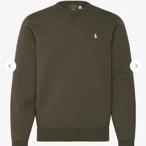 Olivgrön sweatshirt från Polo Ralph Lauren - Snygg olivgrön sweatshirt från Polo Ralph Lauren med klassisk rund halsringning och broderad vit logga på bröstet. Tröjan har långa ärmar och ribbade muddar vid ärmslut och nederkant. Perfekt för en avslappnad och stilren look.
