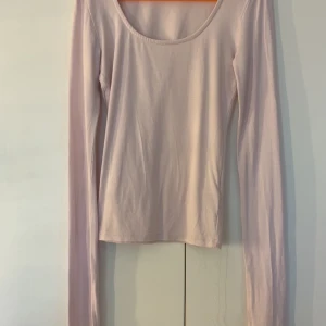 Ljusrosa långärmad topp Gina Tricot - Supersöt ljusrosa långärmad topp från Gina Tricot i stretchig bomullsmix. Modellen är tight med rund halsringning och har slits vid ärmsluten för en extra detalj. Perfekt att styla med jeans eller kjol för en clean look.