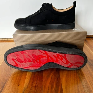 Svarta Christian Louboutin sneakers i mock - Säljer ett par stilrena Christian Louboutin sneakers i svart mocka. Diskret och elegant design med den klassiska röda sulan – perfekt för dig som vill ha ett lyxigt men clean uttryck. Andvända en gång och pris kan diskuteras 
