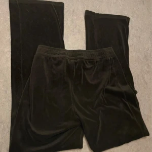 Svarta mjukisbyxor i sammet - Svarta mjukisbyxor i mjuk och glansig sammetskänsla. Byxorna har resår i midjan och raka ben med relaxed fit. Perfekta för chill dagar eller när du vill vara extra bekväm. Snyggt minimalistiska och lätta att matcha med allt. Är lite slitna på knäna. Pris kan diskuteras.