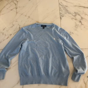 Ljusblå tröja från Polo Ralph Lauren - Snygg ljusblå tröja från Polo Ralph Lauren med klassisk rund halsringning och broderad logga på bröstet. Storlek: 158 - 170 (14-16)