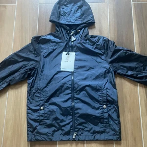 Ny Moncler vattentät vindjacka - Moncler Vindjacka i nyskick - aldrig använd. Storlek M men kan passa S. Väldigt clean och sällsynt modell. Den är gjord av vattentåligt och väldigt skönt material samt sitter sjukt bra på kroppen. Passar alla outfits och matchar med alla färger. Kan frakta samt mötas upp!