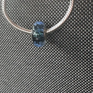 Pandora blå glaspärla till armband - Snygg Pandora-pärla i blått glas med silverdetaljer. Pärlan har ett coolt skimrande mönster och passar perfekt på ett Pandora-armband. Metallinfattningen är i äkta silver (925). Ger en unik touch till ditt smycke!