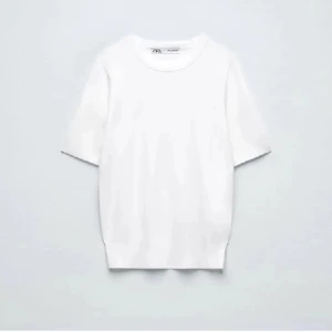 Vit basic t-shirt från Zara - Klassisk vit t-shirt från Zara med rund halsringning och korta ärmar. Enkel och stilren design i mjuk bomull som passar perfekt till jeans eller shorts. Ett måste i garderoben för en clean look.