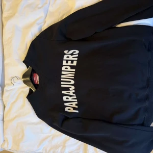 Svart fleece-tröja Parajumpers L - Svart fleece-tröja från Parajumpers i storlek L. Tröjan har en klassisk rund halsringning och stor vit logga tryckt över bröstet. Perfekt för dig som gillar stilrena och sportiga plagg med en clean look. Endast använd 2 gånger så väldigt bra skick!