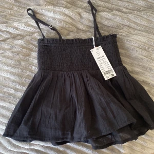 Topp - Supersöt svart linnetopp med smockad överdel och tunna justerbara axelband. Säljer pågrund av att den är för liten. Nypris 179kr😗💋❤️✌️