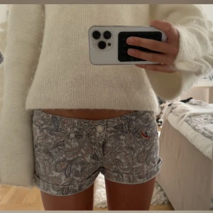 Mönstrade shorts  - Snygga grå shorts med paisleymönster i olika nyanser. De har klassisk knappstängning och fickor framtill. Perfekta för varma dagar när du vill ha en chill och trendig look.