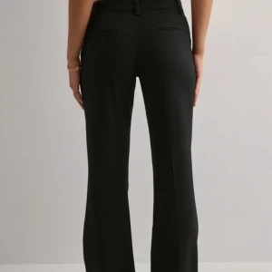 Svarta low waist kostymbyxor med bootcut - Snygga svarta kostymbyxor med bootcut-silhuett och klassiska fickor bak. Byxorna har bälteshällor och stängs med dragkedja och knapp framtill. Perfekta för en clean och stilren look. Använda endast 1 gång