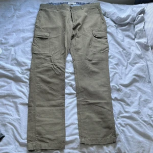 Beiga cargopants med raka ben - Säljer ett par beiga cargopants med raka ben och stora fickor på sidorna.